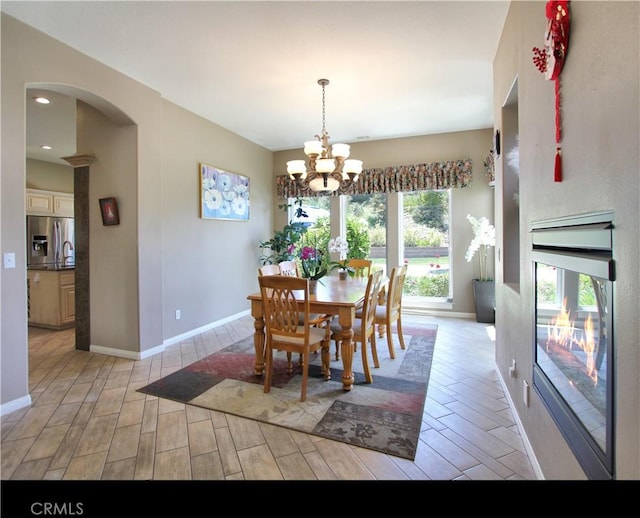 12949 Pinewood Ln, Yucaipa, CA 92399 - dining area featuring wood tiled floors, arched walkways, a chandelier, baseboards, and recessed lighting