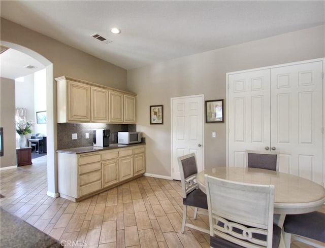 12949 Pinewood Ln, Yucaipa, CA 92399 - kitchen featuring arched walkways, light brown cabinets, backsplash, light wood finished floors, and baseboards