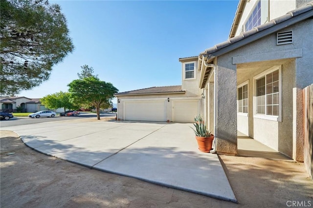 6688 Banyan Ave, Hesperia, CA 92345 - view of home's exterior featuring stucco siding, concrete driveway, a tile roof, and a garage