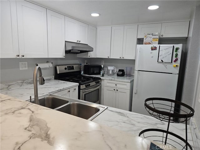 3532 W Stonepine Ln Unit B, Anaheim, CA 92804 - kitchen with gas range, freestanding refrigerator, under cabinet range hood, black microwave, and white cabinetry