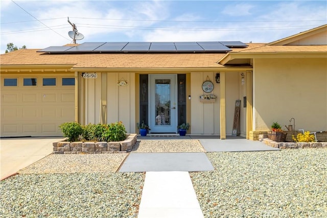 26190 Ridgemoor Rd, Menifee, CA 92586 - view of exterior entry featuring roof mounted solar panels, a garage, and board and batten siding