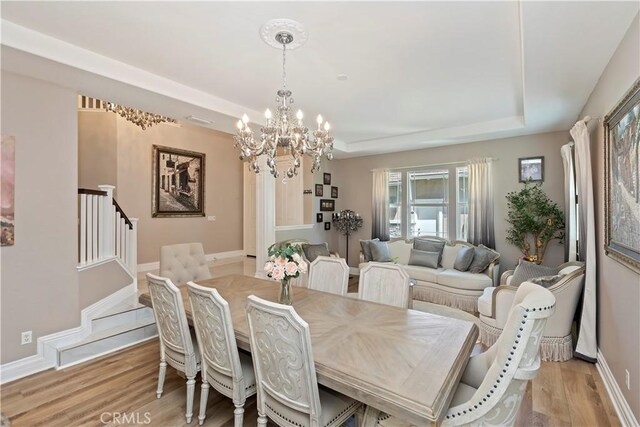 8851 Soothing Ct, Corona, CA 92883 - dining area with a tray ceiling, a chandelier, light wood-type flooring, and stairs
