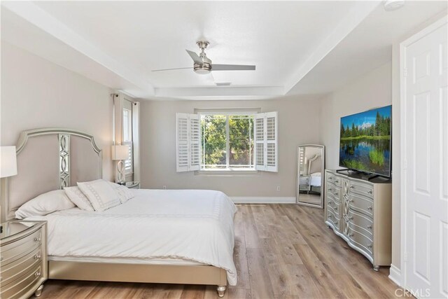 8851 Soothing Ct, Corona, CA 92883 - bedroom featuring a tray ceiling, light wood-style flooring, ceiling fan, and baseboards
