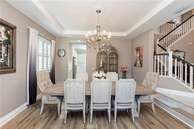 8851 Soothing Ct, Corona, CA 92883 - dining room featuring a chandelier, a raised ceiling, stairway, and wood finished floors