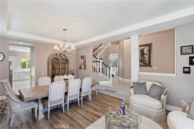 8851 Soothing Ct, Corona, CA 92883 - dining space featuring a chandelier, light wood-type flooring, stairway, and a tray ceiling