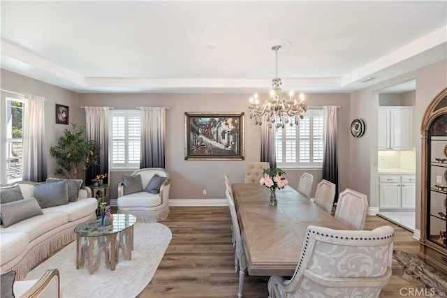 8851 Soothing Ct, Corona, CA 92883 - dining space with a chandelier, a tray ceiling, plenty of natural light, and wood finished floors