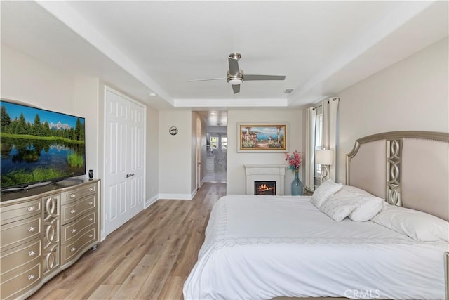 8851 Soothing Ct, Corona, CA 92883 - bedroom with a raised ceiling, light wood-style floors, baseboards, connected bathroom, and a ceiling fan