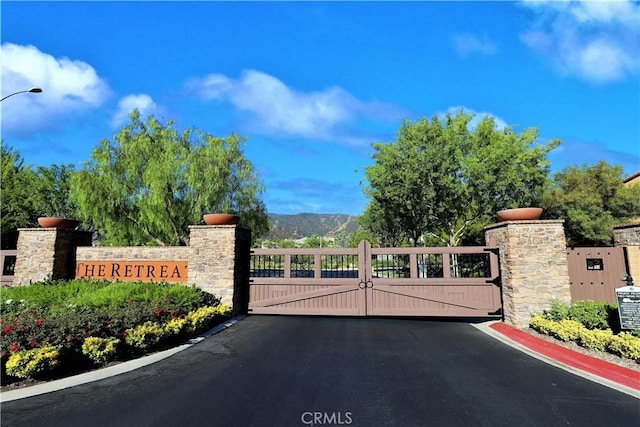 8851 Soothing Ct, Corona, CA 92883 - view of asphalt street with a gate, curbs, a gated entry, and street lights