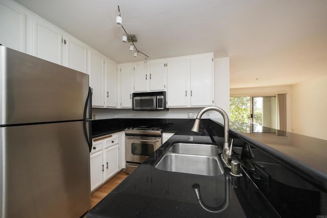7753 Caminito Encanto Unit 102, Carlsbad, CA 92009 - kitchen featuring appliances with stainless steel finishes, a sink, dark countertops, white cabinetry, and light wood finished floors