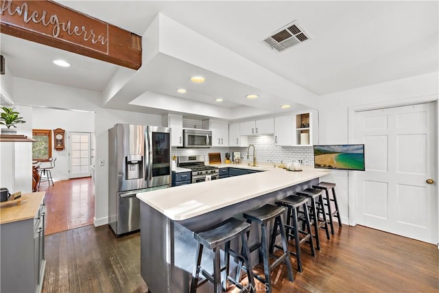31342 Silverado Canyon Rd, Silverado Canyon, CA 92676 - kitchen with appliances with stainless steel finishes, a peninsula, dark wood-type flooring, tasteful backsplash, and a breakfast bar