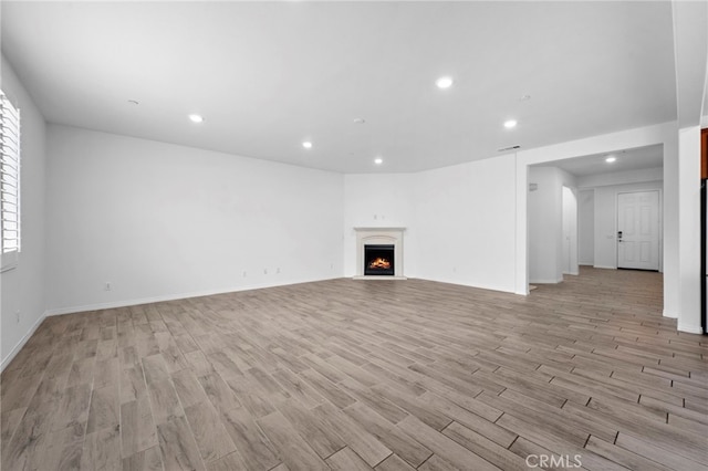 6864 Ripple Ct, Jurupa Valley, CA 91752 - unfurnished living room with recessed lighting, light wood finished floors, a warm lit fireplace, and baseboards