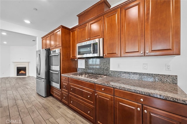 6864 Ripple Ct, Jurupa Valley, CA 91752 - kitchen with appliances with stainless steel finishes, tasteful backsplash, light wood-style floors, a warm lit fireplace, and recessed lighting