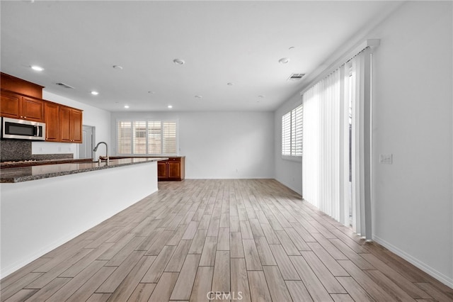 6864 Ripple Ct, Jurupa Valley, CA 91752 - kitchen with stainless steel microwave, plenty of natural light, light wood-style flooring, dark stone counters, and recessed lighting