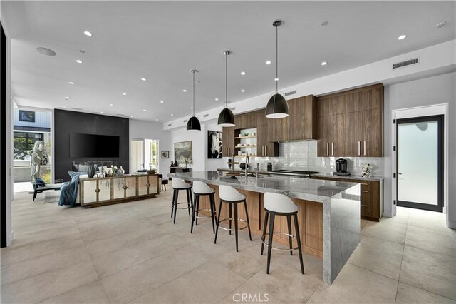 25057 Lewis And Clark Rd, Hidden Hills, CA 91302 - kitchen featuring modern cabinets, a sink, decorative backsplash, a large island with sink, and a breakfast bar