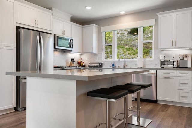 2896 Via Alta Pl, San Diego, CA 92108 - kitchen featuring stainless steel appliances, white cabinetry, dark wood-style floors, a breakfast bar, and decorative backsplash