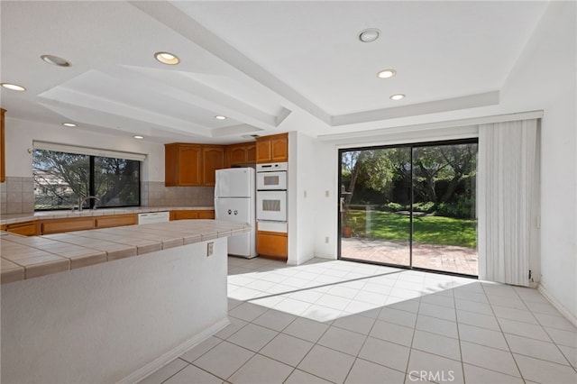 2207 Inverness Ct, Oxnard, CA 93036 - kitchen featuring white appliances, tile countertops, plenty of natural light, a raised ceiling, and recessed lighting