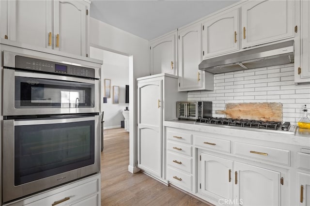 7209 Copper Creek Way, Bakersfield, CA 93308 - kitchen featuring under cabinet range hood, stainless steel appliances, tasteful backsplash, light wood-type flooring, and white cabinets