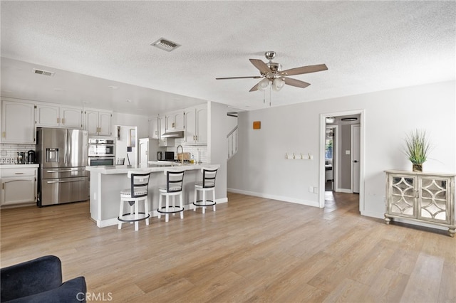 7209 Copper Creek Way, Bakersfield, CA 93308 - kitchen with appliances with stainless steel finishes, a breakfast bar area, a peninsula, a ceiling fan, and tasteful backsplash