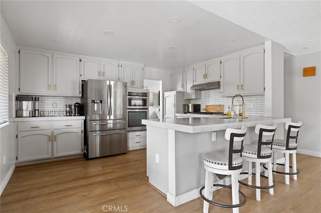 7209 Copper Creek Way, Bakersfield, CA 93308 - kitchen with stainless steel appliances, a peninsula, under cabinet range hood, and tasteful backsplash