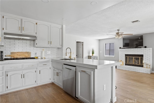 7209 Copper Creek Way, Bakersfield, CA 93308 - kitchen with stainless steel dishwasher, a sink, a peninsula, a ceiling fan, and a fireplace