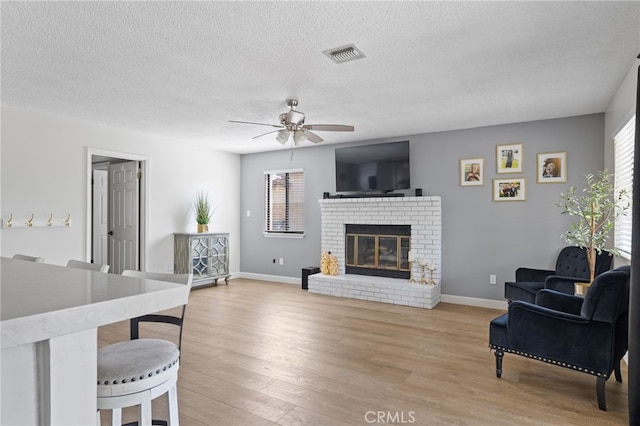 7209 Copper Creek Way, Bakersfield, CA 93308 - living area with ceiling fan, light wood finished floors, a brick fireplace, baseboards, and a textured ceiling