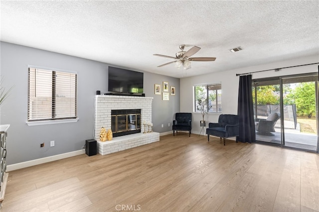 7209 Copper Creek Way, Bakersfield, CA 93308 - living area with a textured ceiling, light wood-style floors, a brick fireplace, a ceiling fan, and baseboards