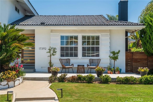 17392 Almelo Ln, Huntington Beach, CA 92649 - rear view of property featuring a tiled roof, a porch, a chimney, a yard, and stucco siding