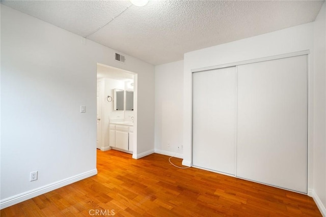 10149 Commerce Ave Unit 8, Tujunga, CA 91042 - unfurnished bedroom with light wood-style flooring, a closet, baseboards, and a textured ceiling