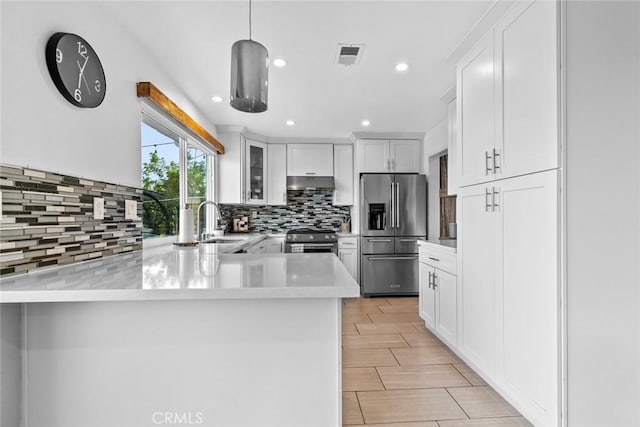 18534 Dylan St, Porter Ranch, CA 91326 - kitchen with appliances with stainless steel finishes, a sink, under cabinet range hood, a peninsula, and decorative backsplash