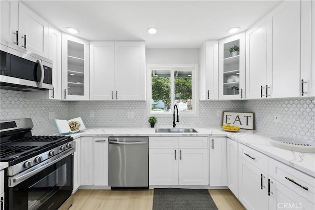 12632 Halcourt Ave, Norwalk, CA 90650 - kitchen with stainless steel appliances, a sink, white cabinetry, light stone counters, and light wood-style floors