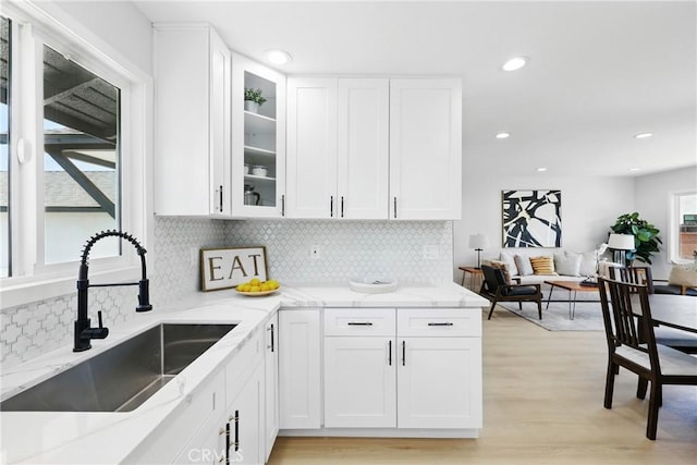 12632 Halcourt Ave, Norwalk, CA 90650 - kitchen with a sink, light stone counters, white cabinetry, glass insert cabinets, and recessed lighting
