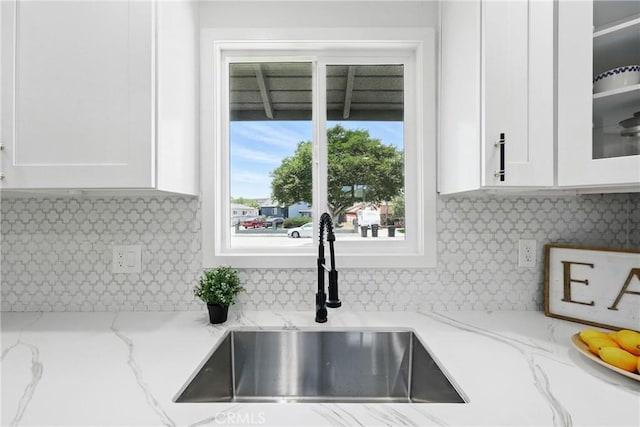 12632 Halcourt Ave, Norwalk, CA 90650 - kitchen with a sink, white cabinetry, glass insert cabinets, backsplash, and light stone counters