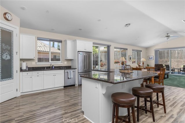 8640 Erika Ct, Atascadero, CA 93422 - kitchen featuring appliances with stainless steel finishes, a sink, light wood-type flooring, white cabinets, and vaulted ceiling
