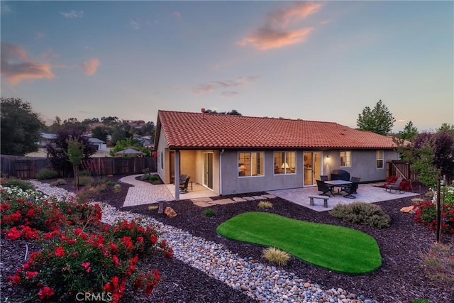 8640 Erika Ct, Atascadero, CA 93422 - back of house at dusk with a tile roof, a patio area, a fenced backyard, and stucco siding
