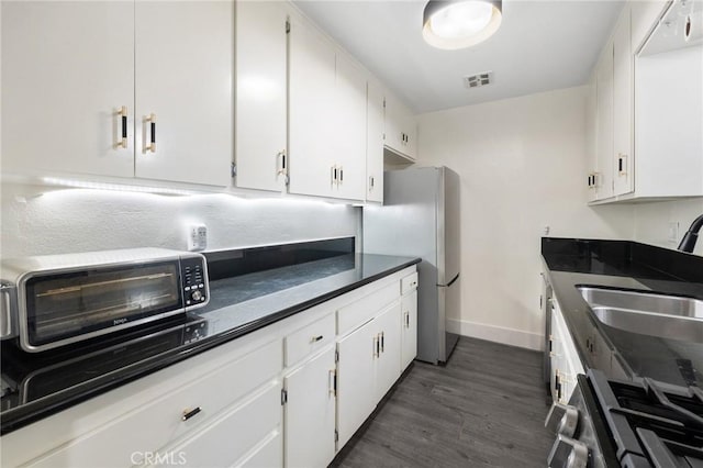 1222 N Olive Dr Unit 409, West Hollywood, CA 90069 - kitchen with stainless steel appliances, a sink, white cabinetry, dark wood-type flooring, and dark countertops