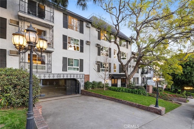 1222 N Olive Dr Unit 409, West Hollywood, CA 90069 - view of apartment building / complex featuring asphalt driveway, an attached garage, and a wall mounted AC