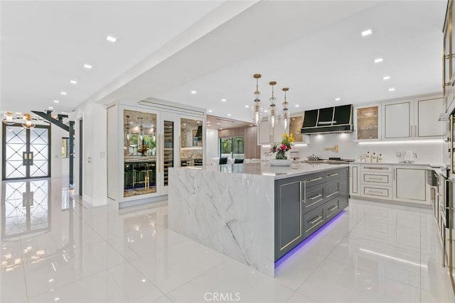2223 Flintridge Dr, Glendale, CA 91206 - kitchen with range hood, gray cabinets, a spacious island, light tile patterned floors, and glass insert cabinets