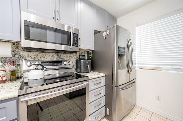 2233 Martin Unit 411, Irvine, CA 92612 - kitchen with stainless steel appliances, decorative backsplash, light tile patterned flooring, and light stone countertops