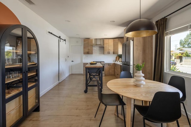 1958 Edgemont St, San Diego, CA 92102 - dining space featuring a barn door, light wood-style flooring, recessed lighting, and baseboards