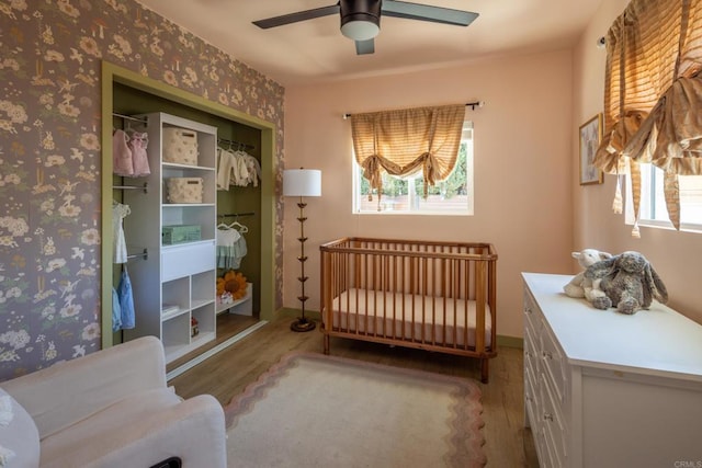 1958 Edgemont St, San Diego, CA 92102 - bedroom with wood finished floors, a closet, wallpapered walls, a ceiling fan, and a nursery area
