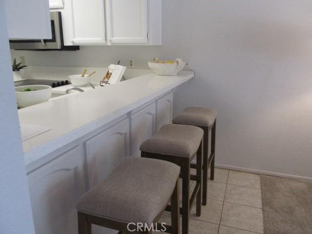 13601 Del Monte Dr Unit M17-46A, Seal Beach, CA 90740 - kitchen featuring white cabinetry, light countertops, baseboards, and light tile patterned floors