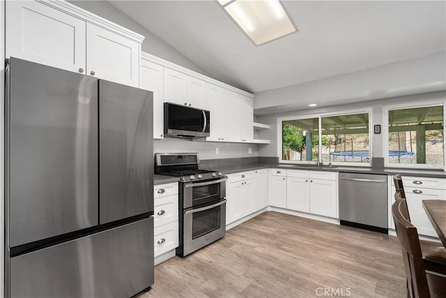 27747 Wakefield Rd, Castaic, CA 91384 - kitchen featuring appliances with stainless steel finishes, vaulted ceiling, dark countertops, open shelves, and light wood-style floors