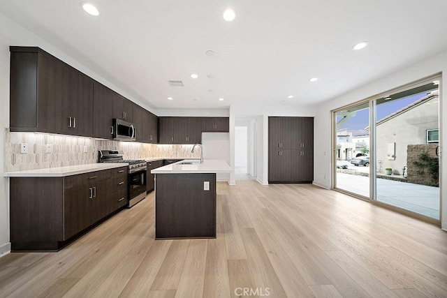 35806 Mccarthy St, Palm Desert, CA 92211 - kitchen with stainless steel appliances, a sink, tasteful backsplash, dark brown cabinets, and light wood-type flooring