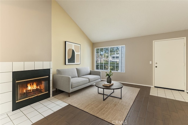 37940 42nd St E Unit 125, Palmdale, CA 93552 - living room featuring dark wood finished floors, a tiled fireplace, high vaulted ceiling, and baseboards