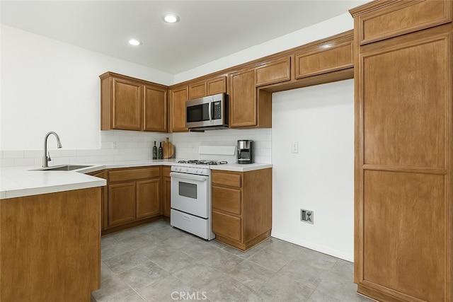 37940 42nd St E Unit 125, Palmdale, CA 93552 - kitchen with a sink, gas range gas stove, stainless steel microwave, brown cabinets, and tasteful backsplash