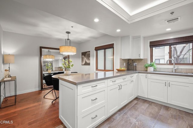 1000 E California Blvd Unit 108, Pasadena, CA 91106 - kitchen with a sink, a peninsula, white cabinets, backsplash, and decorative light fixtures