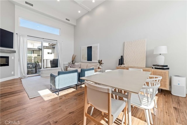 2713 Carnegie Ln Unit B, Redondo Beach, CA 90278 - dining area with a towering ceiling, light wood-style floors, a glass covered fireplace, baseboards, and recessed lighting