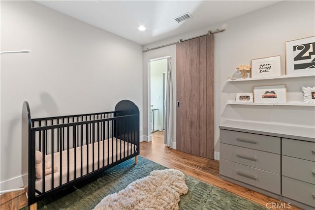2713 Carnegie Ln Unit B, Redondo Beach, CA 90278 - bedroom with wood finished floors, a crib, baseboards, and a barn door
