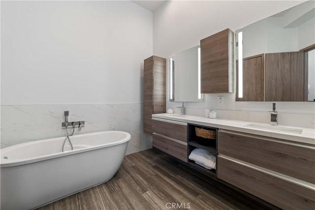 2713 Carnegie Ln Unit B, Redondo Beach, CA 90278 - bathroom featuring double vanity, tile walls, a freestanding tub, a wainscoted wall, and wood finished floors