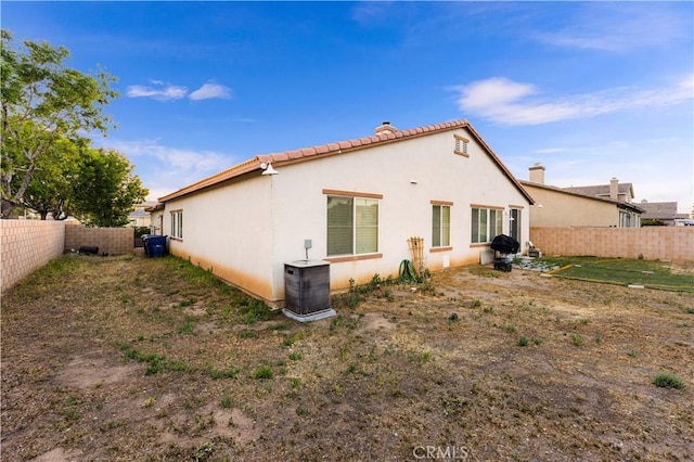 39202 Nicole Dr, Palmdale, CA 93551 - back of house featuring a fenced backyard, central AC, stucco siding, and a chimney